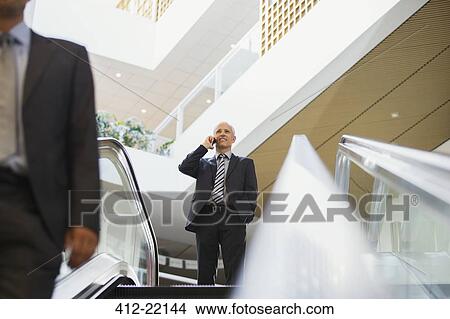 Businessman talking on cell phone at top of stairs in office building View Large Photo Image Picture - Businessman talking on cell phone at top of stairs in office building. Fotosearch