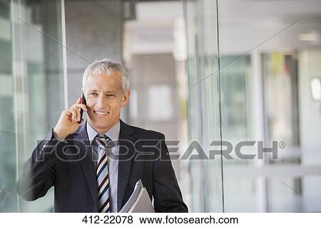 Businessman talking on cell phone in office building View Large Photo Image Stock Photo - Businessman talking on cell phone in office building . Fotosearch