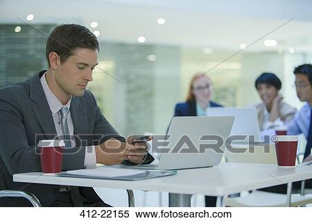 Businessman using cell phone in office building cafe View Large Photo Image Stock Photography - Businessman using cell phone in office building cafe. Fotosearch