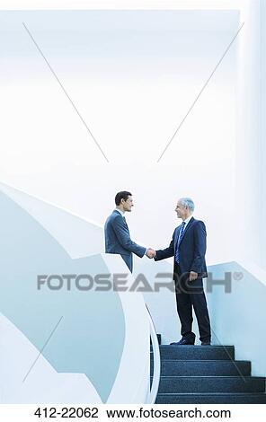 Businessmen shaking hands on stairs of office building View Large Photo Image Stock Image - Businessmen shaking hands on stairs of office building. Fotosearch
