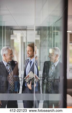 Businessmen talking in office building View Large Photo Image Stock Image - Businessmen talking in office building. Fotosearch