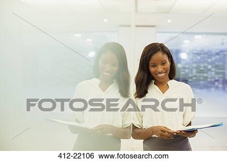 Businesswoman carrying documents in office building View Large Photo Image Stock Photograph - Businesswoman carrying documents in office building. Fotosearch