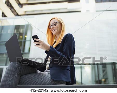 Businesswoman sitting on bench using cell phone View Large Photo Image Stock Image - Businesswoman sitting on bench using cell phone. Fotosearch