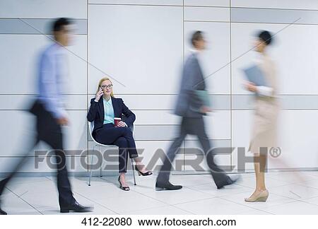 Stock Image - Businesswoman talking on cell phone in office. Fotosearch