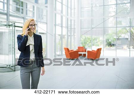 Businesswoman talking on cell phone in office building View Large Photo Image Stock Image - Businesswoman talking on cell phone in office building. Fotosearch