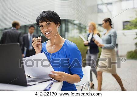 Businesswoman talking on headset at table in office building View Large Photo Image Stock Image - Businesswoman talking on headset at table in office building. Fotosearch