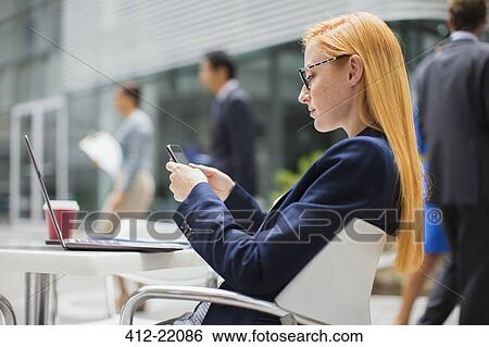 Businesswoman using cell phone at table outside View Large Photo Image Stock Photograph - Businesswoman using cell phone at table outside. Fotosearch
