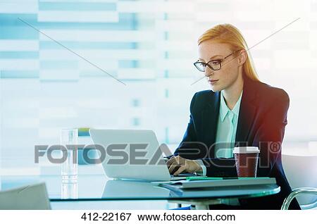 Businesswoman working on laptop in office building cafe View Large Photo Image Stock Photo - Businesswoman working on laptop in office building cafe. Fotosearch