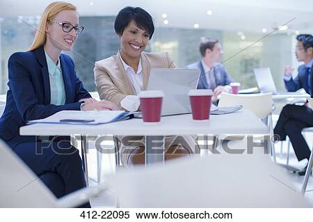 Stock Photography - Businesswomen working on laptop at table . Fotosearch