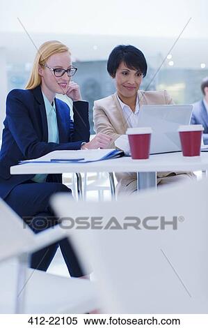 Businesswomen working on laptop at table View Large Photo Image Stock Photography - Businesswomen working on laptop at table. Fotosearch