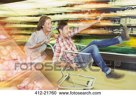 Blurred view of couple playing with shopping cart in grocery store View Large Photo Image Stock Image - Blurred view of couple playing with shopping cart in grocery store. Fotosearch
