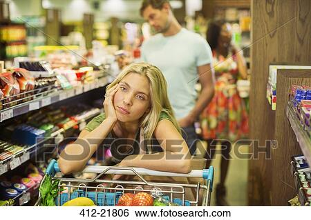 Stock Photograph - Bored woman shopping in grocery store. Fotosearch