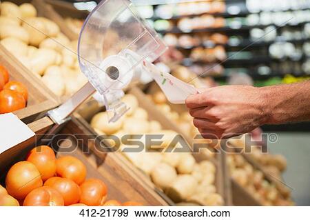 Stock Photo - Close up of man taking plastic bag in produce section of grocery store. Fotosearch