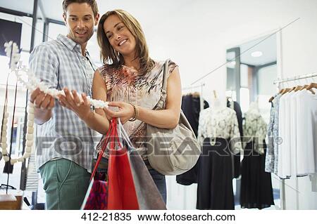 Stock Photography - Couple admiring jewelry in clothing store. Fotosearch