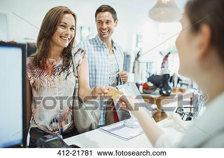 Stock Image - Couple paying with credit card in clothing store. Fotosearch