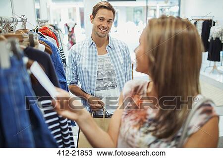 Stock Image - Couple shopping together in clothing store. Fotosearch