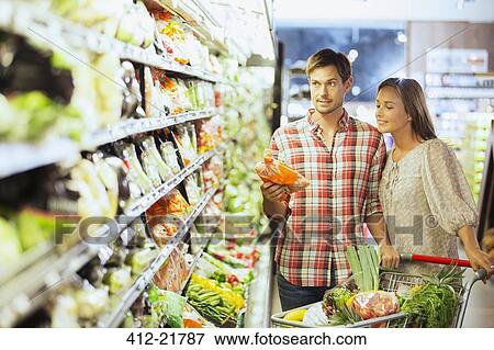 Couple shopping together in grocery store View Large Photo Image Stock Photo - Couple shopping together in grocery store. Fotosearch