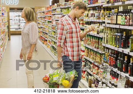 Couple shopping together in grocery store View Large Photo Image Stock Photo - Couple shopping together in grocery store. Fotosearch