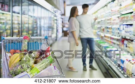 Defocussed view of couple shopping in grocery store View Large Photo Image Stock Photo - Defocussed view of couple shopping in grocery store. Fotosearch