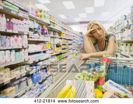 Frustrated woman pushing shopping cart in grocery store View Large Photo Image Picture - Frustrated woman pushing shopping cart in grocery store. Fotosearch