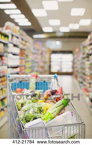 Picture - Full shopping cart in grocery store aisle. Fotosearch
