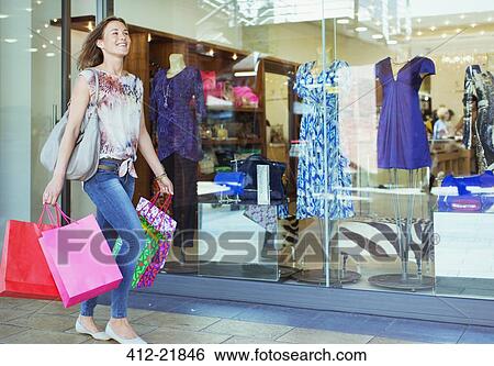 Stock Photograph - Woman carrying shopping bags in shopping mall. Fotosearch