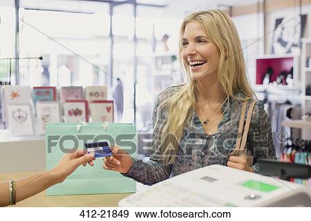 Stock Photo - Woman paying with credit card in clothing store. Fotosearch