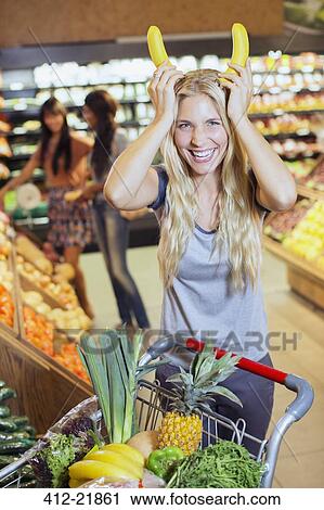Woman playing with bananas while shopping in grocery store View Large Photo Image Stock Image - Woman playing with bananas while shopping in grocery store. Fotosearch