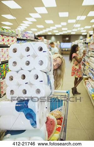 Stock Photograph - Woman pushing full shopping cart in grocery store. Fotosearch