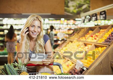 Woman talking on cell phone in grocery store View Large Photo Image Stock Image - Woman talking on cell phone in grocery store. Fotosearch