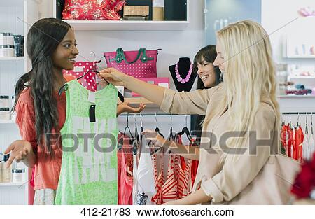 Stock Image - Women shopping together in clothing store. Fotosearch