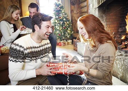 Stock Image - Couple exchanging gifts on Christmas. Fotosearch