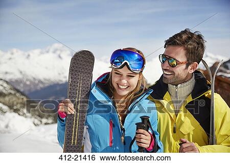 Stock Photograph - Couple holding skis together. Fotosearch