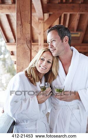 Stock Image - Couple in bathrobes hugging on balcony . Fotosearch