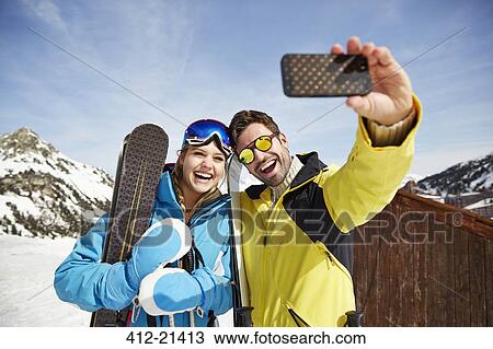 Stock Image - Couple taking picture together in the snow. Fotosearch
