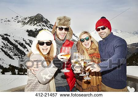 Couples celebrating with drinks in the snow View Large Photo Image Stock Photo - Couples celebrating with drinks in the snow. Fotosearch