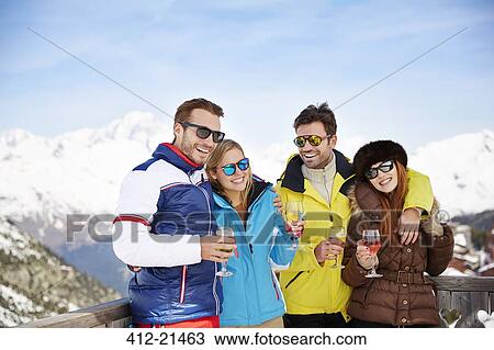 Stock Image - Friends celebrating with drinks in the snow. Fotosearch