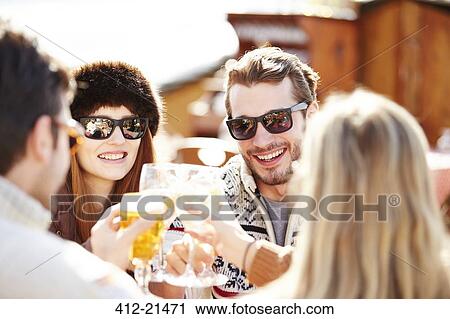 Stock Image - Friends celebrating with drinks in the snow. Fotosearch