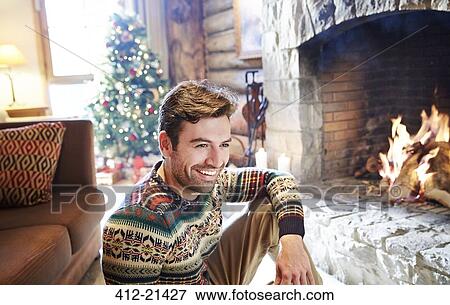 Stock Photo - Man in warm sweater enjoying fireplace. Fotosearch