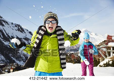 Stock Image - Siblings having snowball fight. Fotosearch