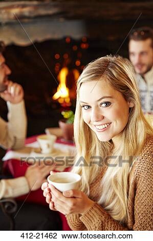 Stock Image - Woman holding hot drink at restaurant. Fotosearch