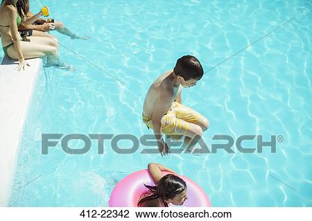 Stock Image - Boy and girl jumping into swimming pool. Fotosearch
