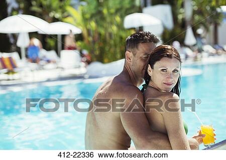 Stock Photograph - Couple relaxing by resort swimming pool. Fotosearch