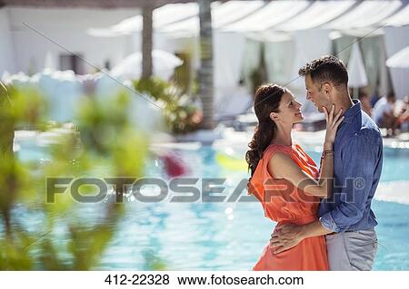 Couple standing face to face by swimming pool View Large Photo Image Stock Photo - Couple standing face to face by swimming pool. Fotosearch