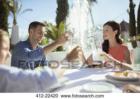 Stock Image - Family raising toast at table outdoors. Fotosearch