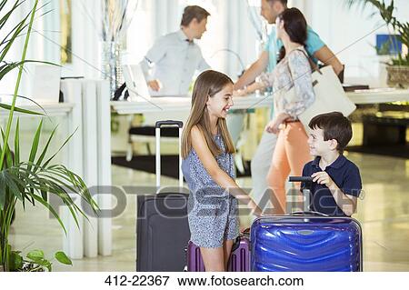 Family with daughter and son standing with suitcases in hotel lobby View Large Photo Image Stock Photo - Family with daughter and son standing with suitcases in hotel lobby. Fotosearch