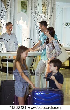 Family with suitcases talking with receptionist in hotel lobby View Large Photo Image Stock Image - Family with suitcases talking with receptionist in hotel lobby. Fotosearch