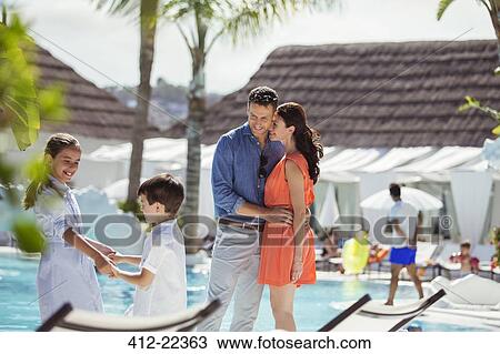 Stock Image - Family with two children by swimming pool. Fotosearch