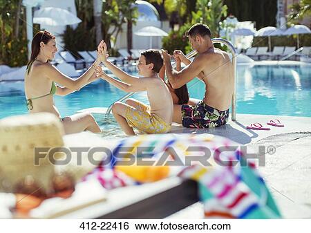 Stock Photograph - Family with two children enjoying themselves by swimming pool. Fotosearch