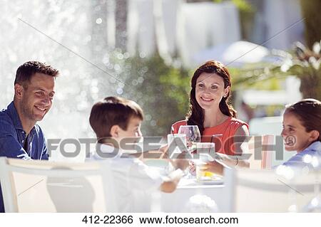Family with two children raising toast at table outdoors View Large Photo Image Stock Photograph - Family with two children raising toast at table outdoors. Fotosearch
